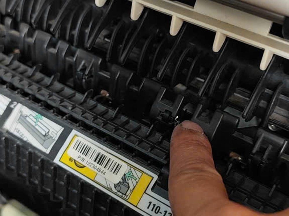 Kỹ thuật viên TechPrint kiểm tra khu vực nạp giấy của máy Ricoh — nơi mảnh giấy sót lại hay mắc kẹt và gây ra SC501.